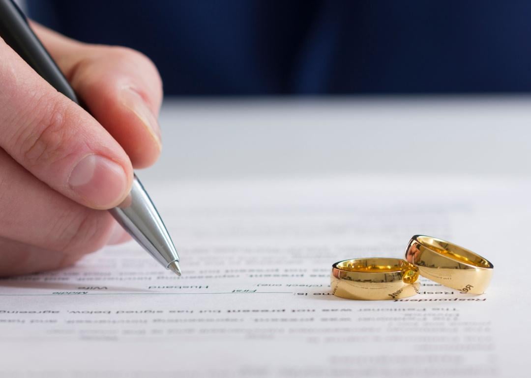 Hand signing document with two gold rings
