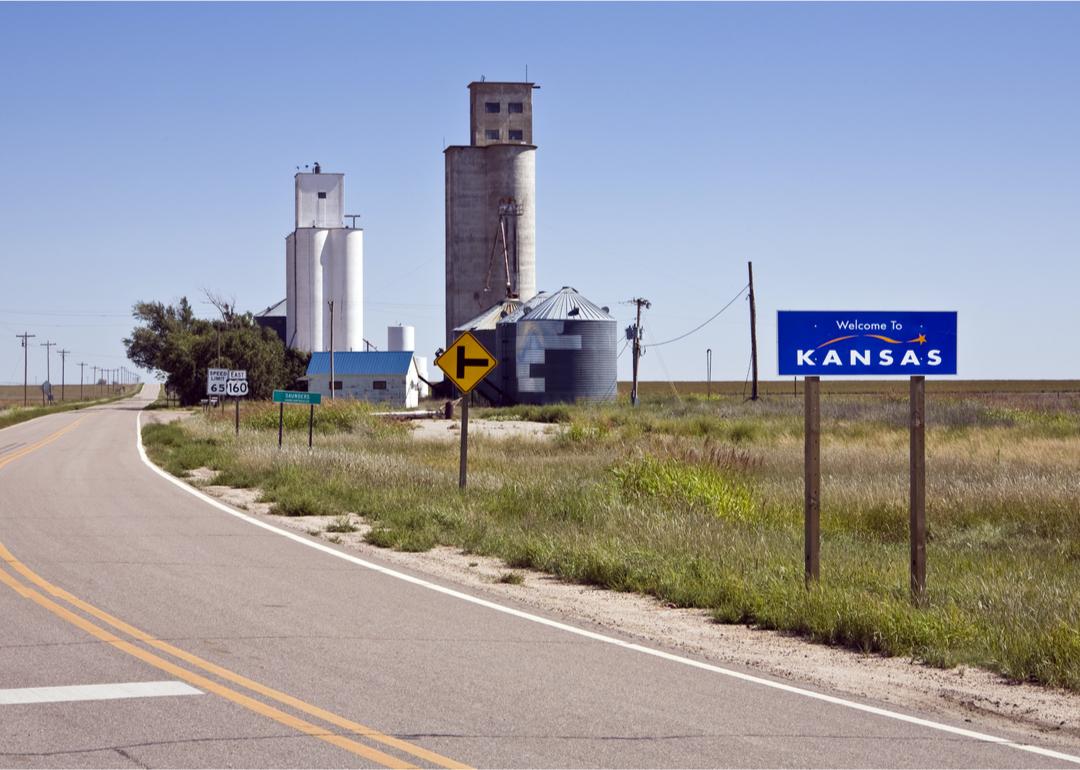 “Welcome to Kansas” sign near Saunders grain elevators.