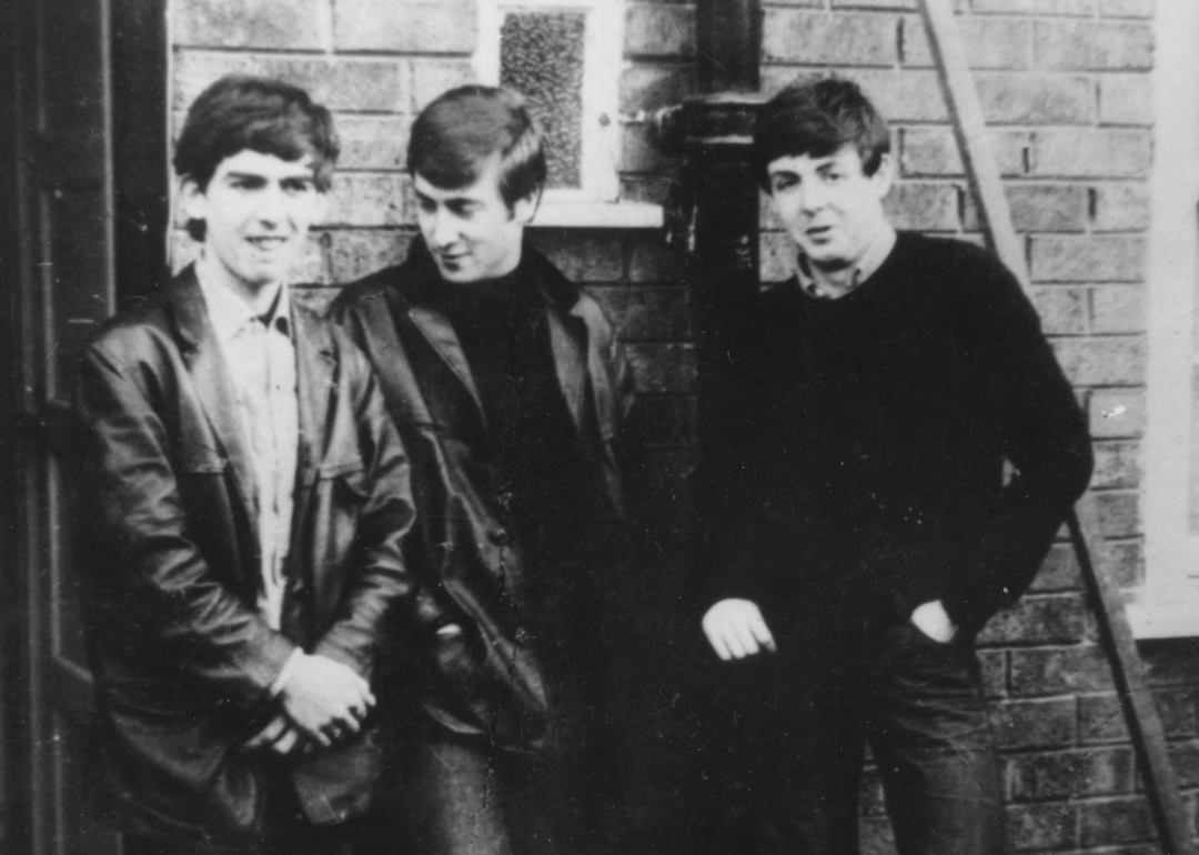 John Lennon, Paul McCartney and George Harrison stand outside of Paul’s home.