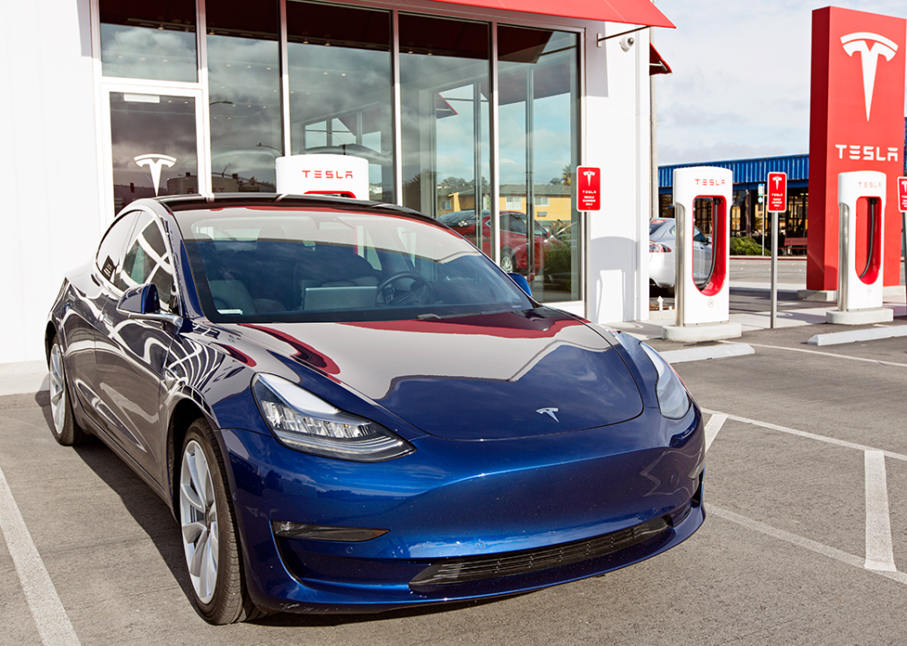 Navy Tesla Model 3 charging at supercharger station.