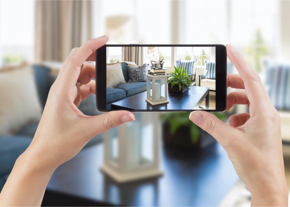 Image shows a hand holding up a smartphone to take a picture of items in a room
