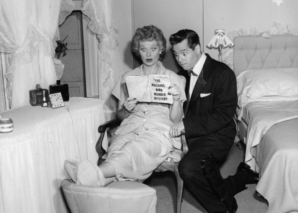 Lucille Ball and Desi Arnaz in the pilot episode of 'I Love Lucy’ reading a book called The Mocking-Bird Murder Mystery with shocked looks on their faces.