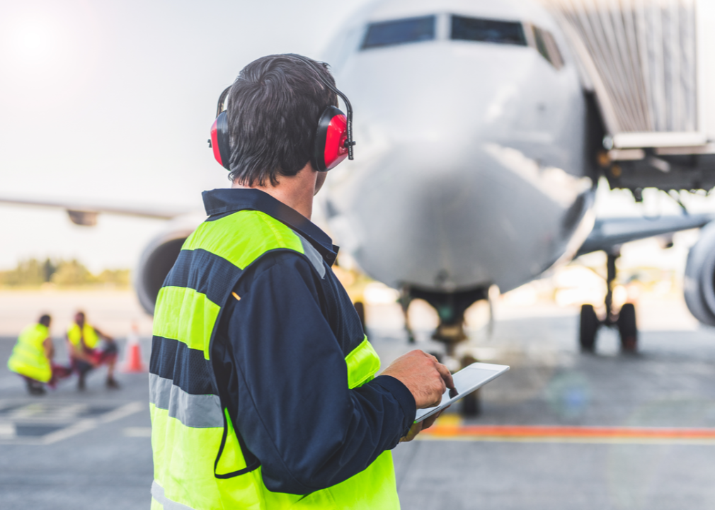 Transportation manager on tarmac checks tablet.