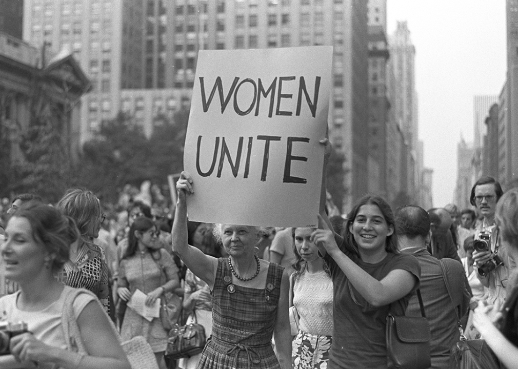 Women hold up a Women Unite sign as they march down Fifth Avenue in New York City.