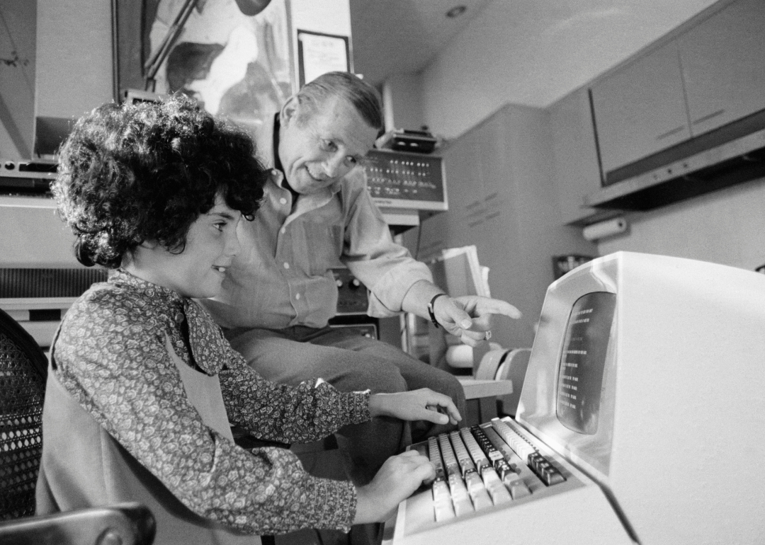 Child reaches for keyboard on personal computer.
