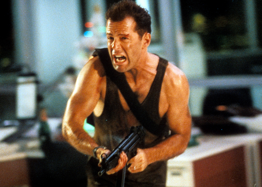 Bruce Willis running with automatic weapon in a scene from the film Die Hard.