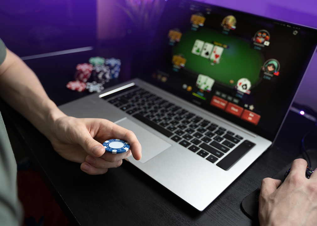 Person playing online poker game on a laptop.