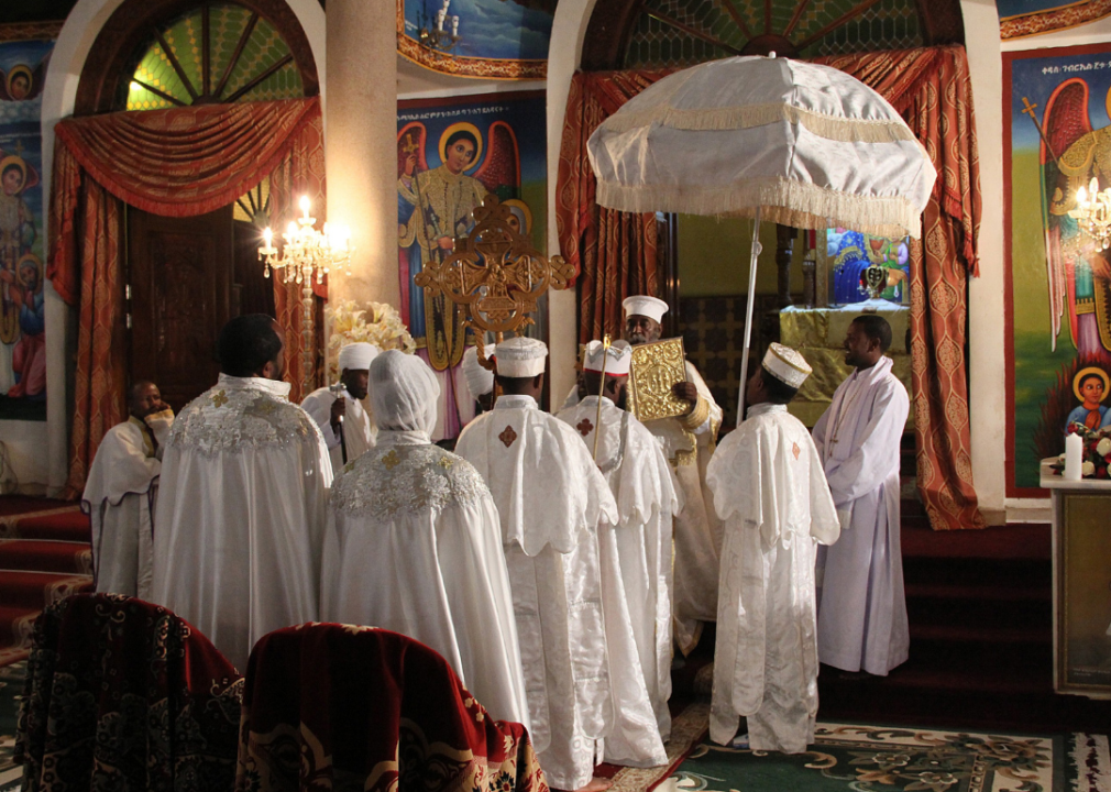 A group of people wearing ornate white robes in a softly lit church.