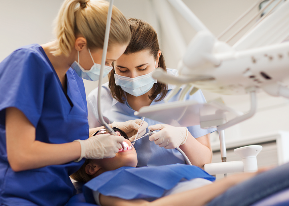 Dentist and dental hygienist assisting patient.