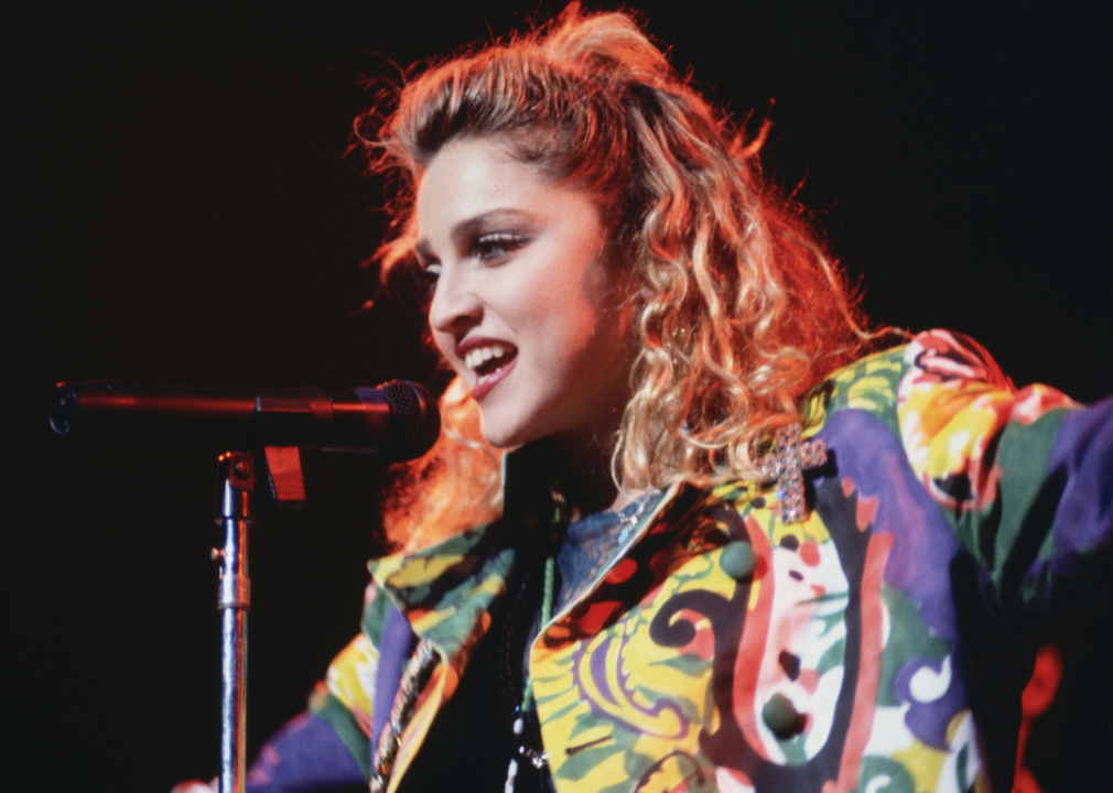 Madonna performing onstage wearing colorful jacket.