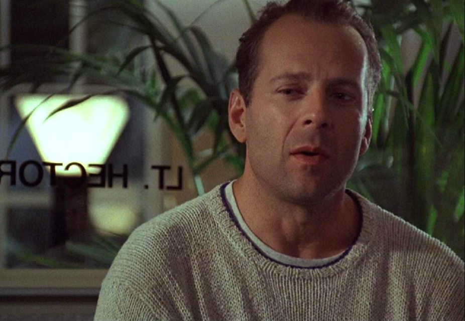 Bruce Willis looks down with a slight smile.