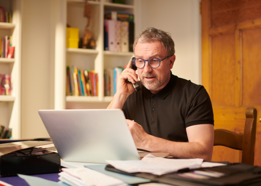 A middle-aged man on the phone at his laptop
