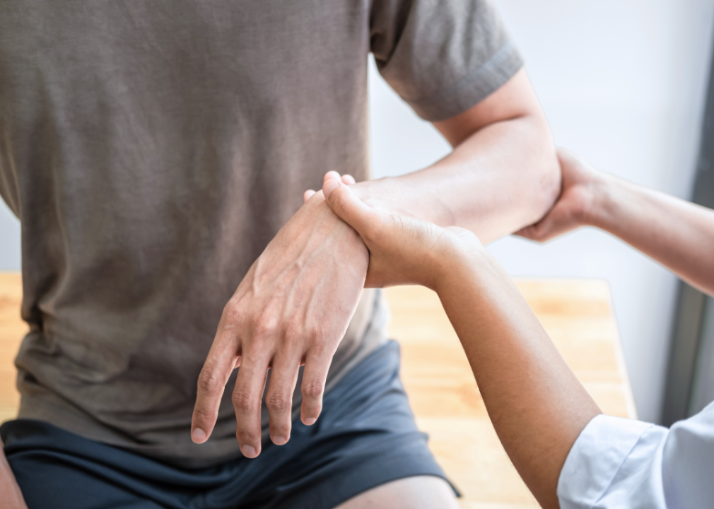 Female physiotherapist examining a man's injured arm.