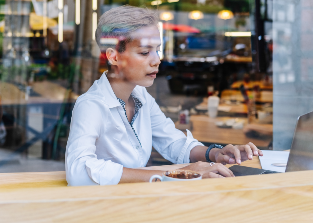 A woman behind a window types on her laptop.