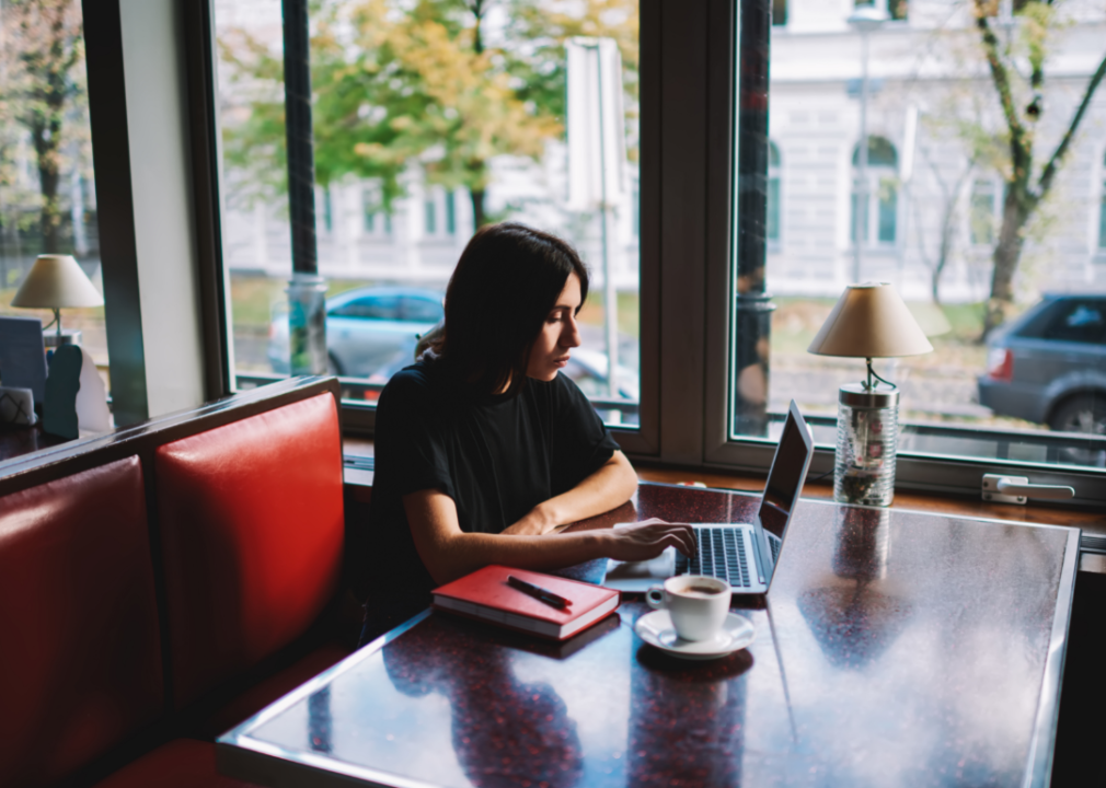 A woman does research on her laptop in a cafe.