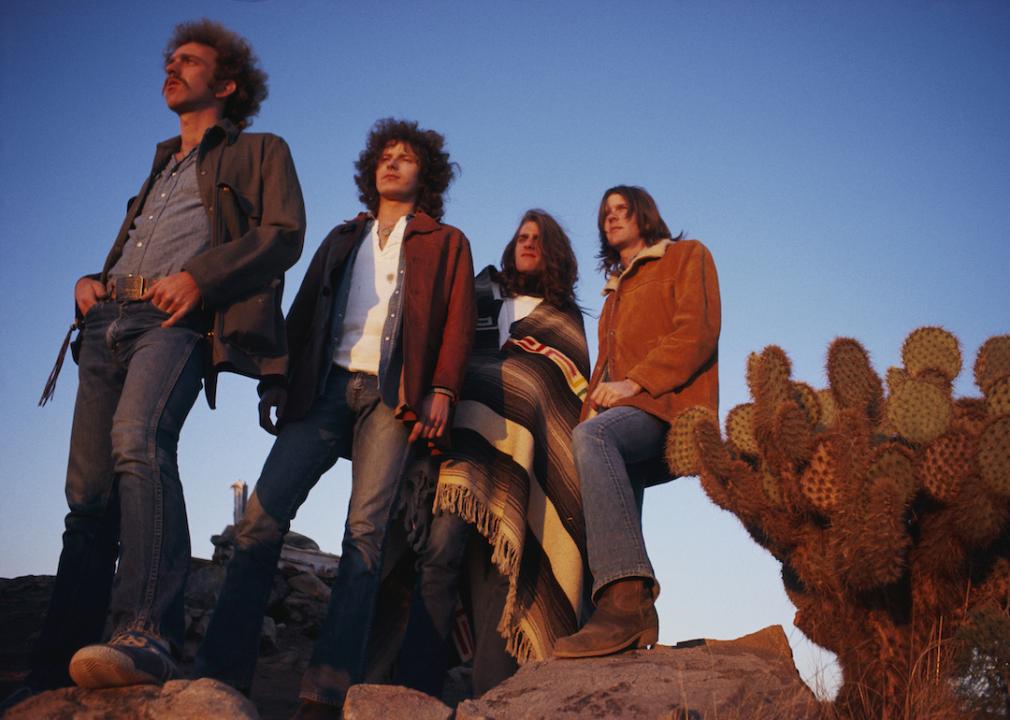 The rock band The Eagles stand in a desert valley, from left to right: Bernie Leadon, Don Henley, Glenn Frey, and Randy Meisner.