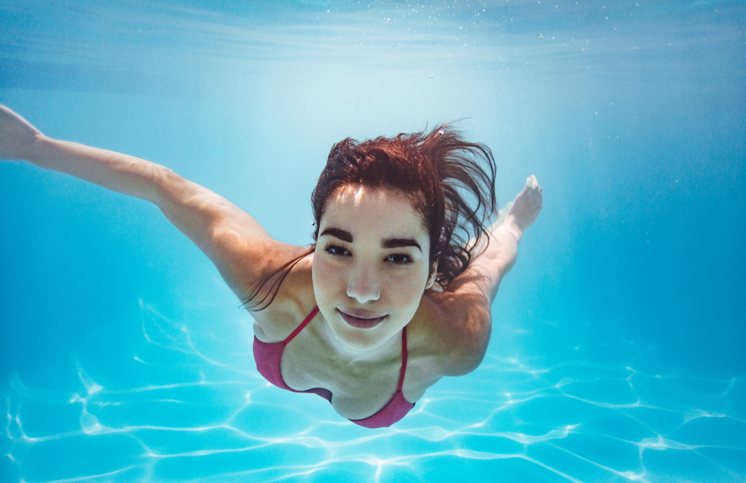 A woman swimming underwater in a pool