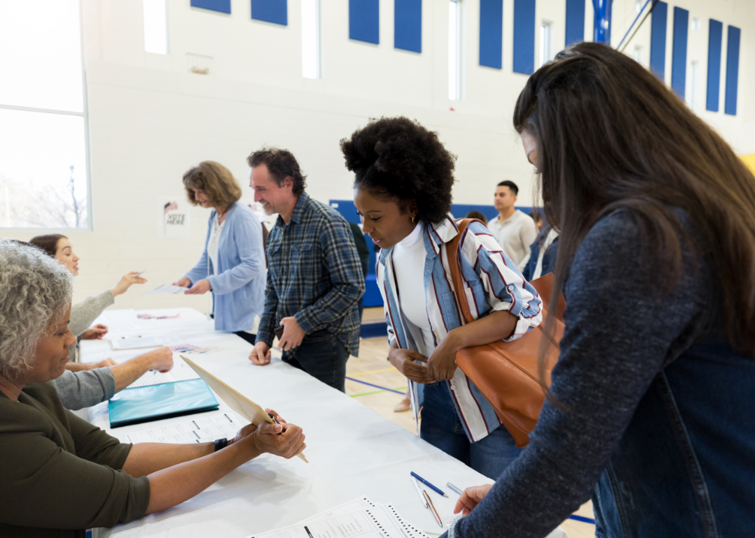 Polling place volunteers assist voters with voting documents