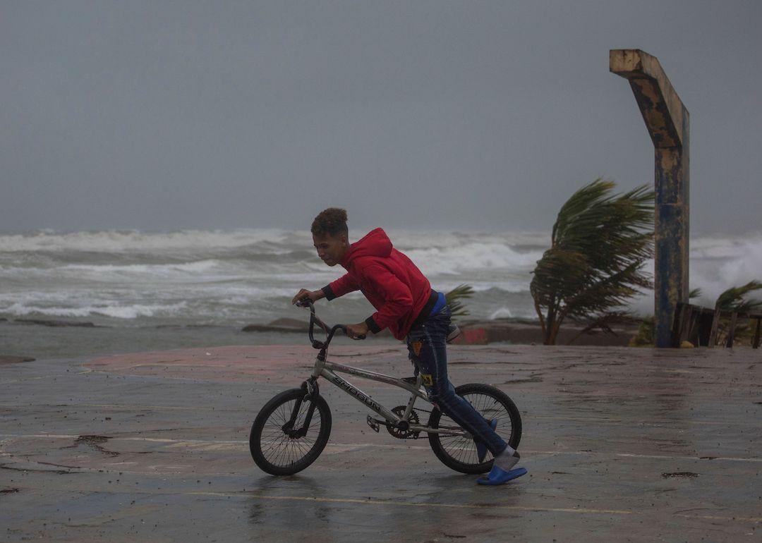  A youth rides his bicycle at the seaside in Nagua, Dominican Republic, on September 19, 2022, as Hurricane Fiona passes through the country. 