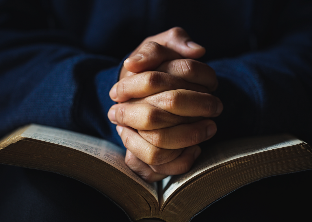 Hands clasped in prayer resting on a book