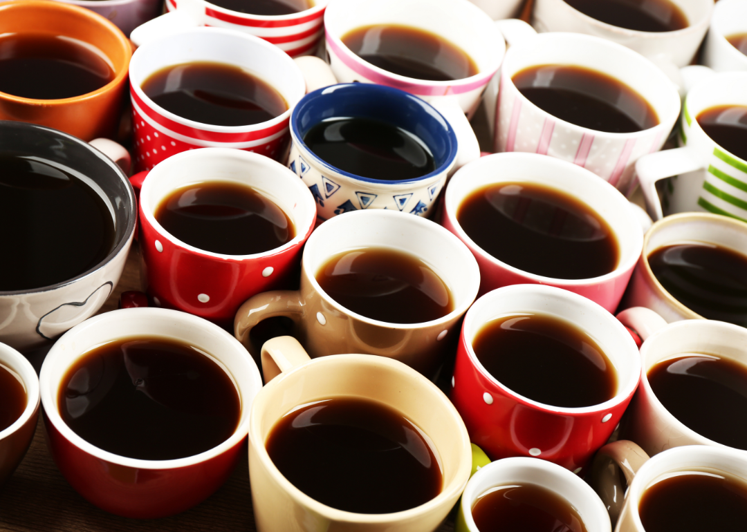 Many cups of coffee in a variety of colorful mugs.