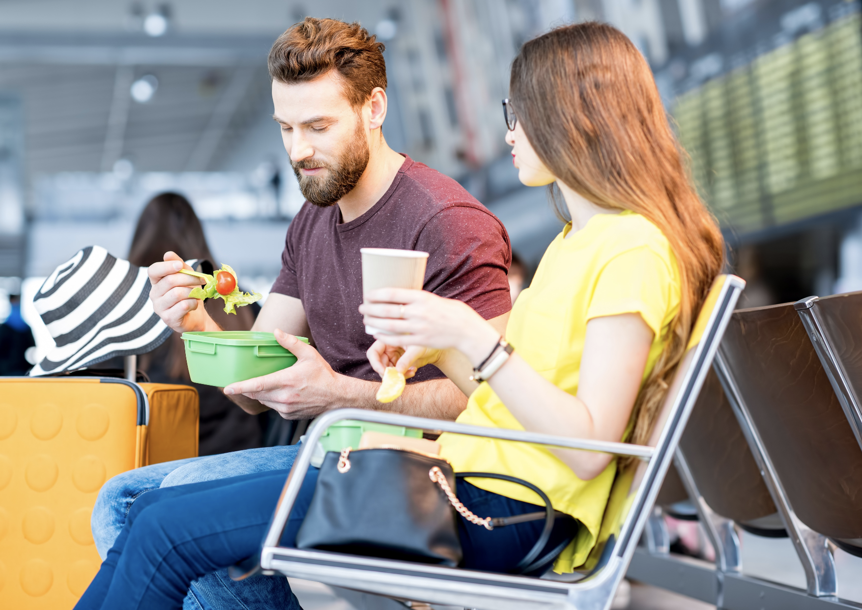 Young couple having a snack with lunch boxes in a airport.