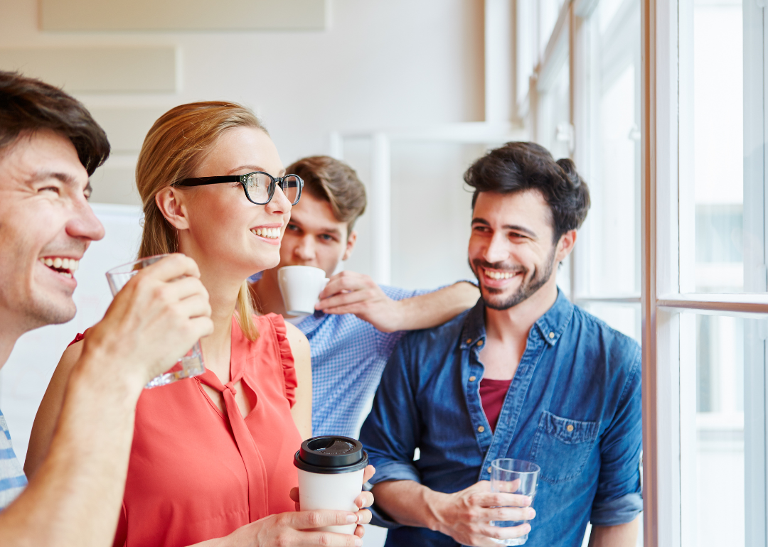 Coworkers smile as they sip coffee on a break.