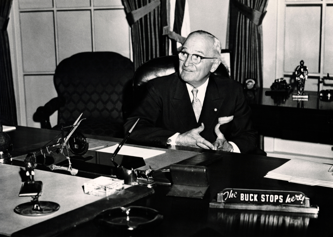 President Harry S. Truman seated at his desk in the White House library.
