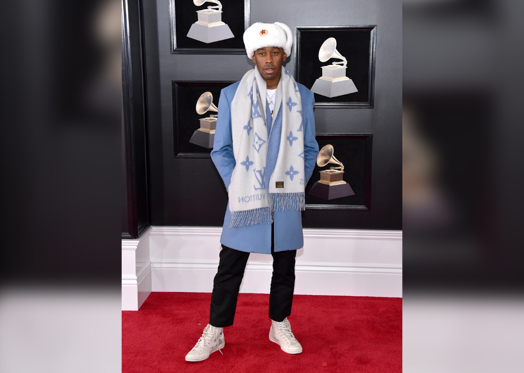 Tyler, the Creator on the red carpet in a light blue suit and white fur hat.