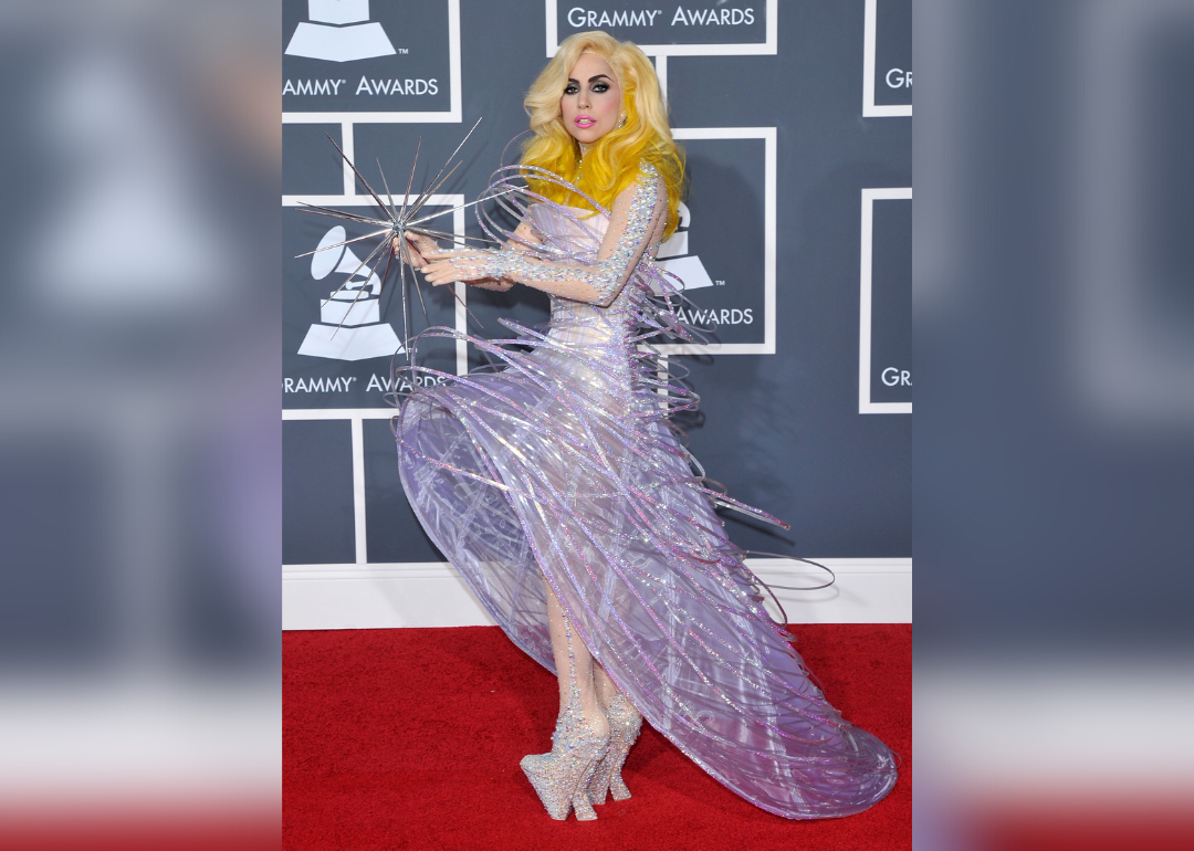 Lady Gaga posing in a pink sparkling gown holding a giant star.