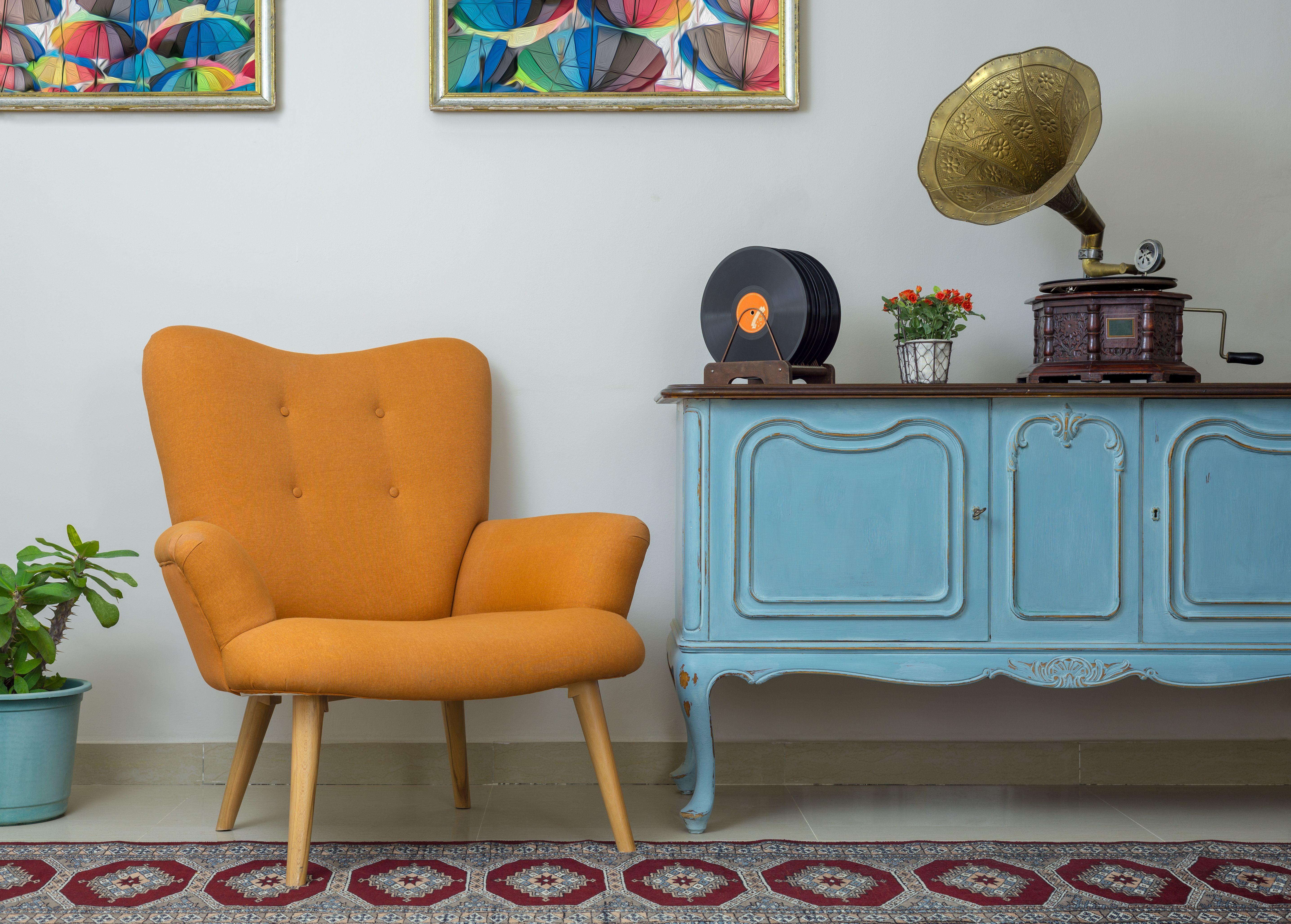 Retro orange armchair, vintage wooden light blue sideboard and old phonograph.