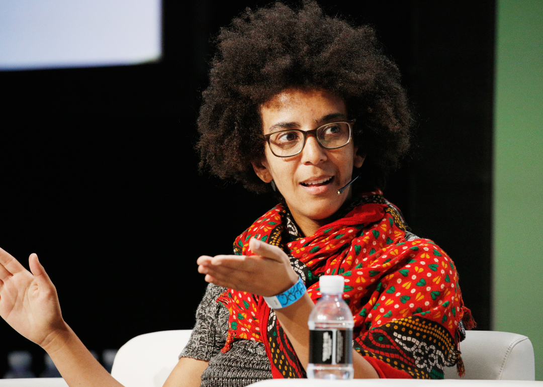 Image shows AI ethics researcher Timnit Gebru seated with arms partially extended