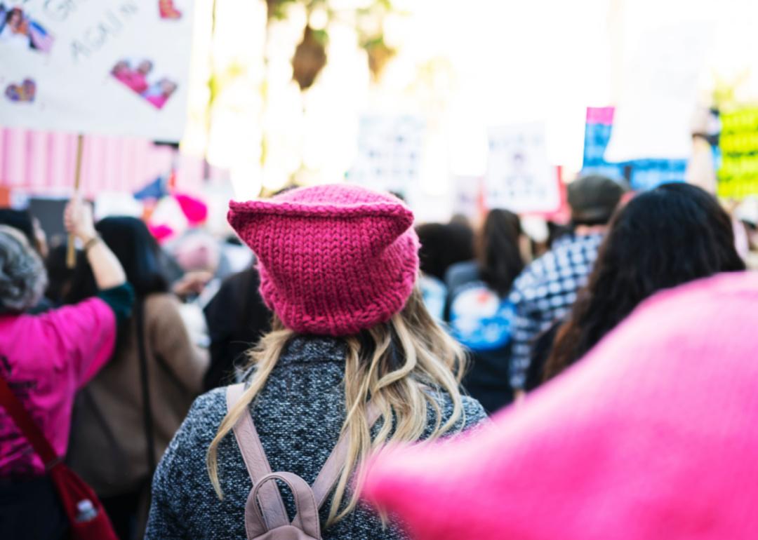 Image shows a rally of people, mostly women, demonstrating for women's rights