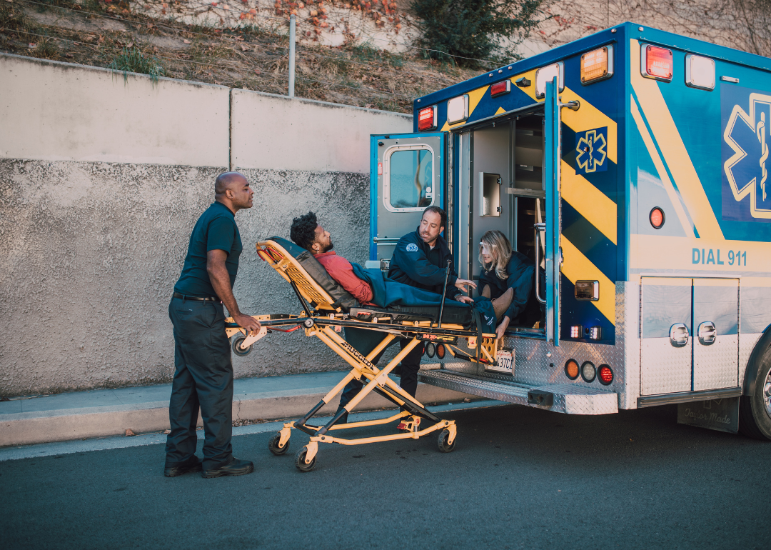 A paramedic loads a man in a stretcher into an ambulance.
