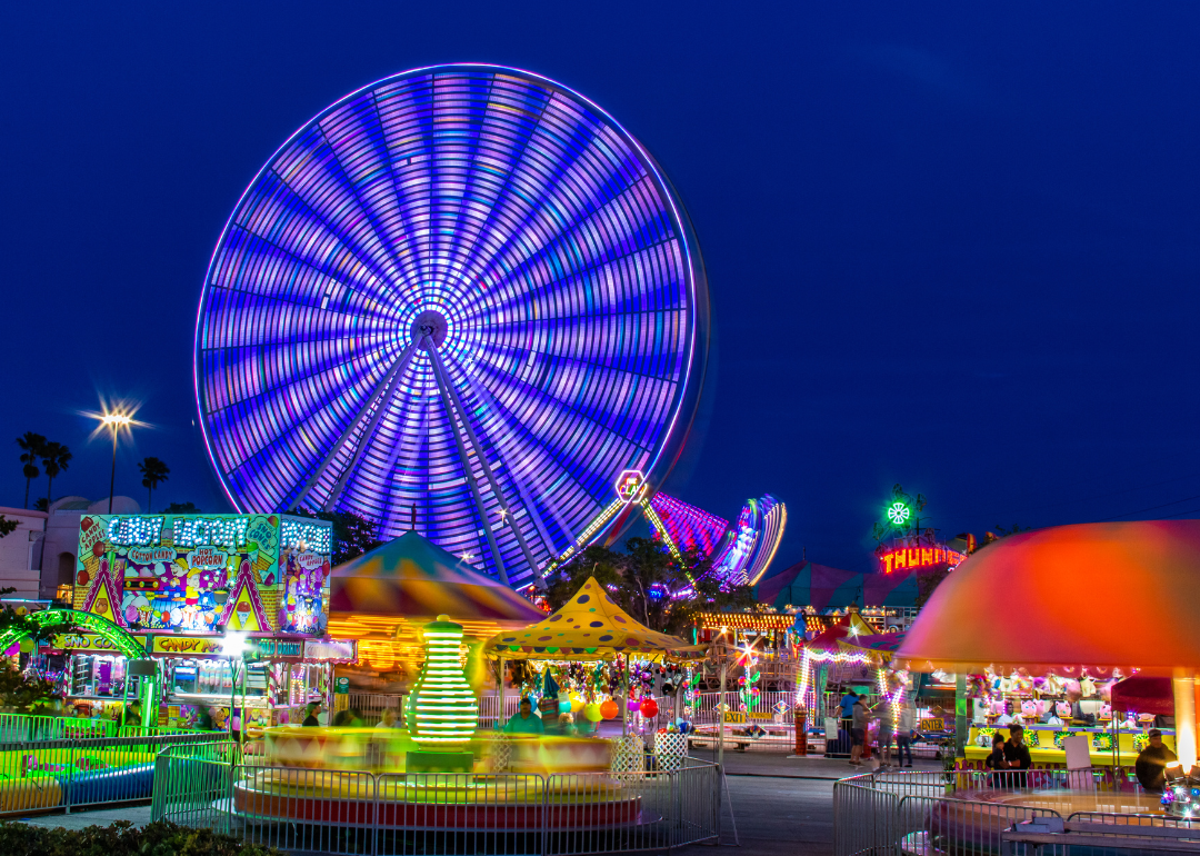 An amusement park with ferris wheel and rides at night.