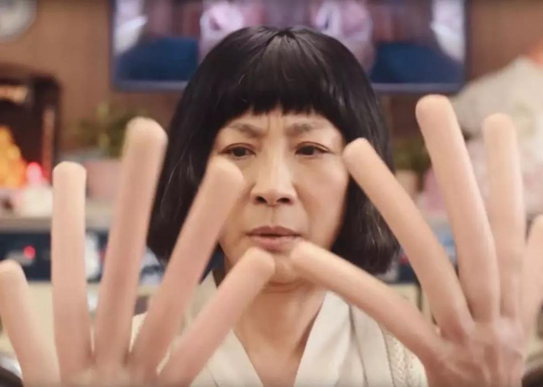Actor Michelle Yeoh looks at her oversized, hot-dog-shaped fingers in 'Everything Everywhere All at Once.'