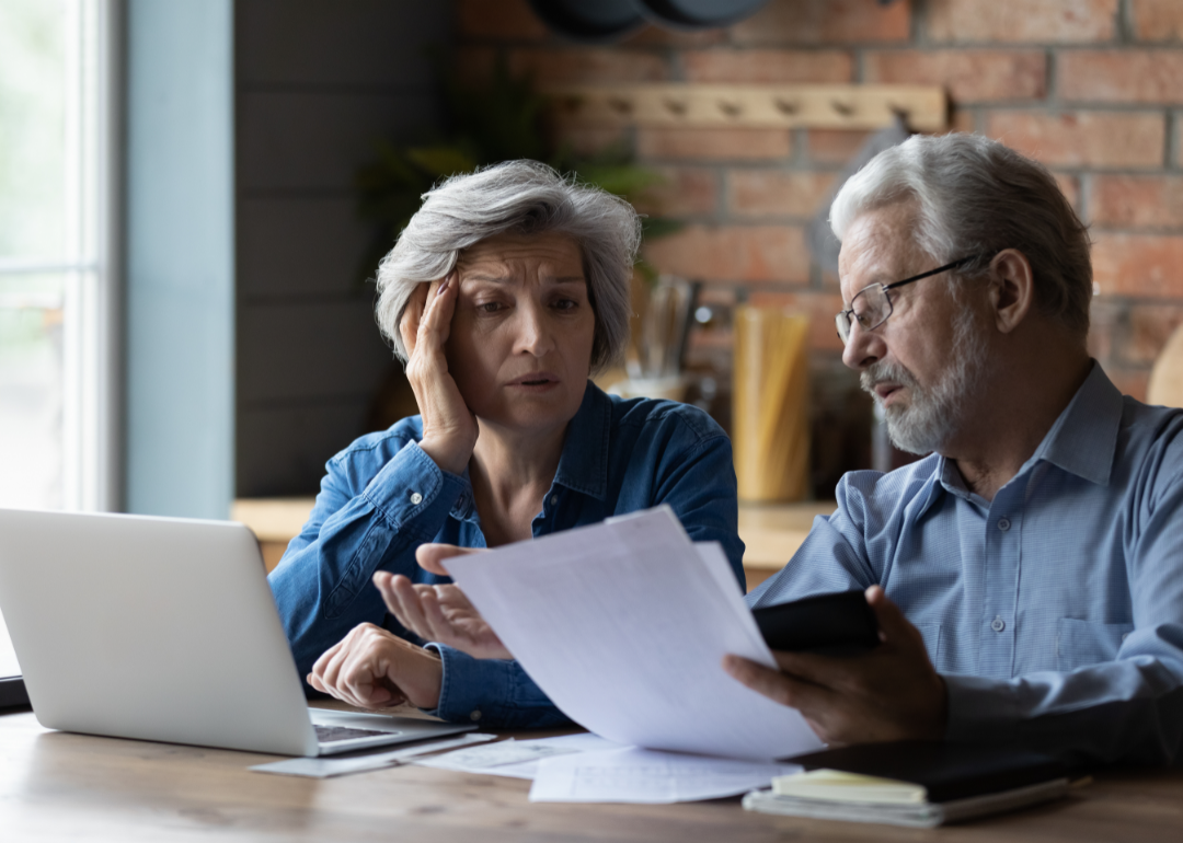 Am older couple looks concerned as they review their finances at home.