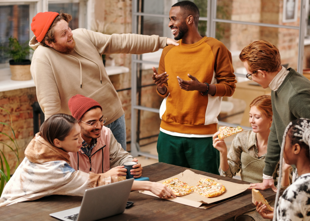 A group of coworkers enthusiastically socialize in an office space.