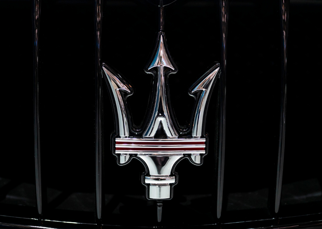 The Maserati logo as seen on the grill of a car.