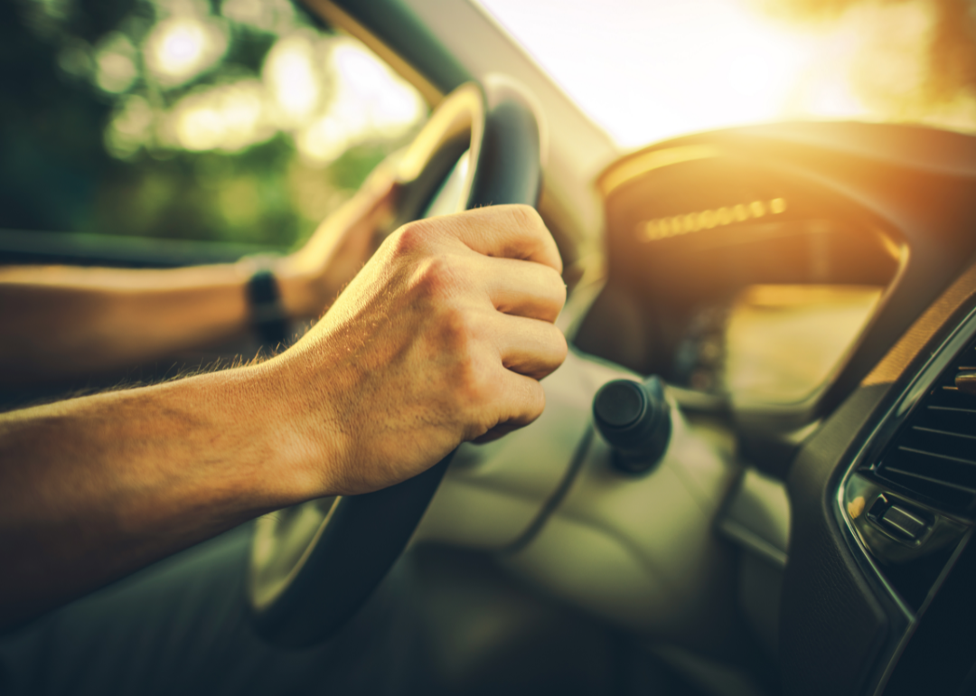 Inside the car with hands on the steering wheel.