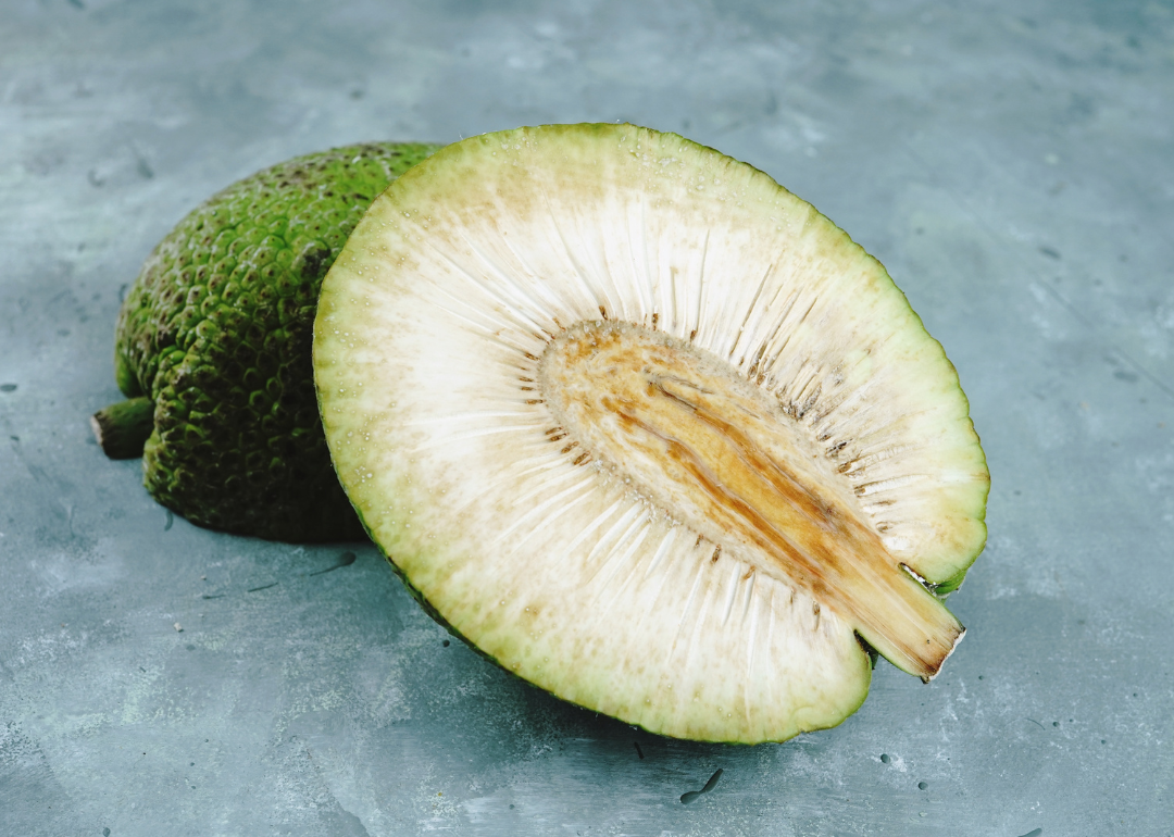 A piece of sliced breadfruit sits on a concrete surface.