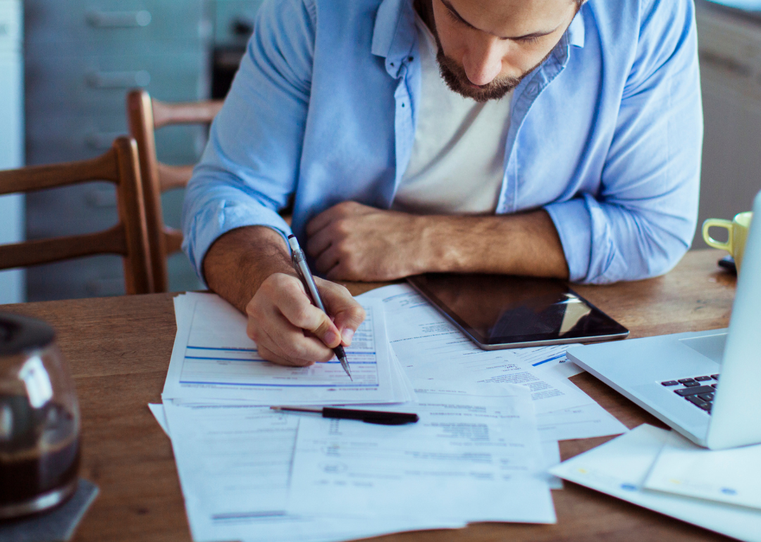 Person checking his financial status using laptop and paperwork.