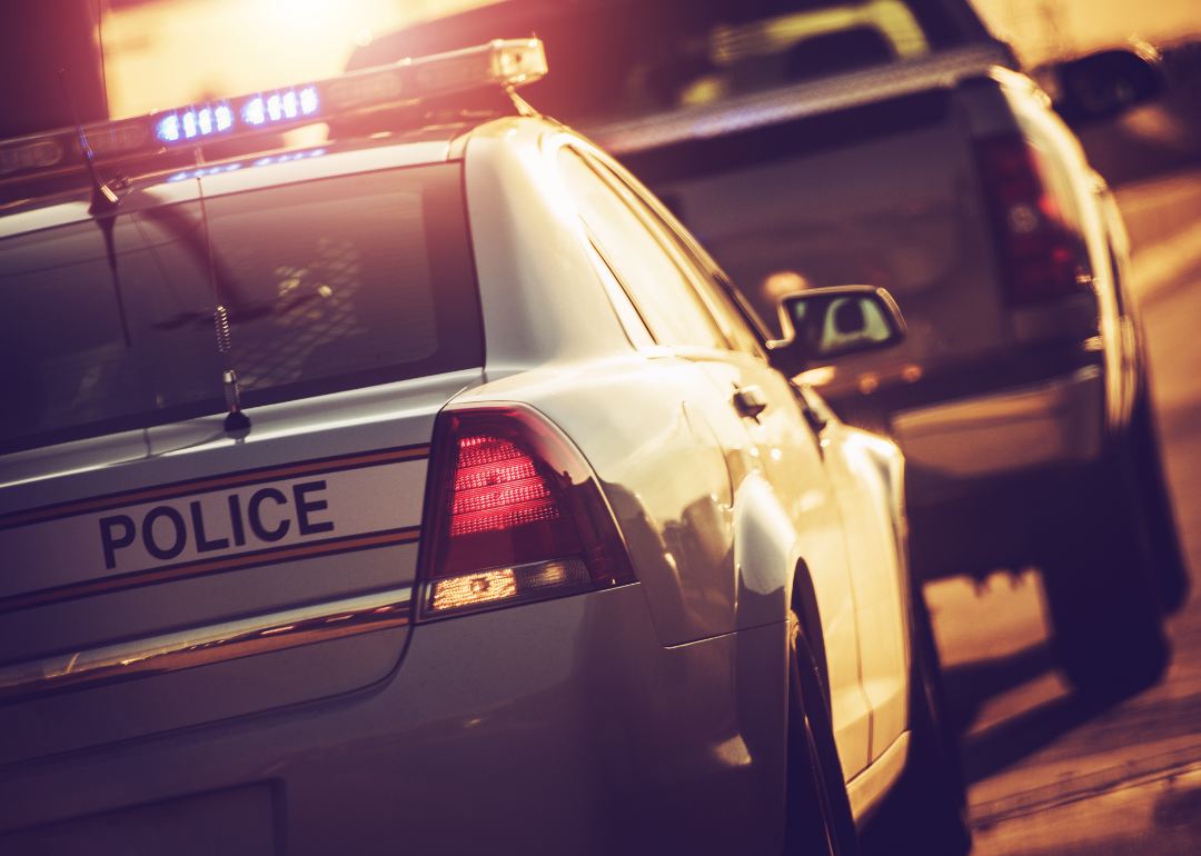 A police car behind a pickup truck at sunset.