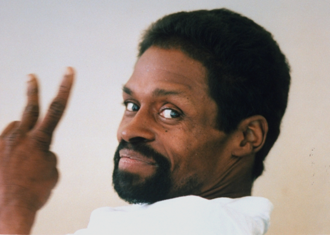 Former pro baseball player Glenn Burke, who was dying of AIDS, holding up fingers in a peace sign at home.