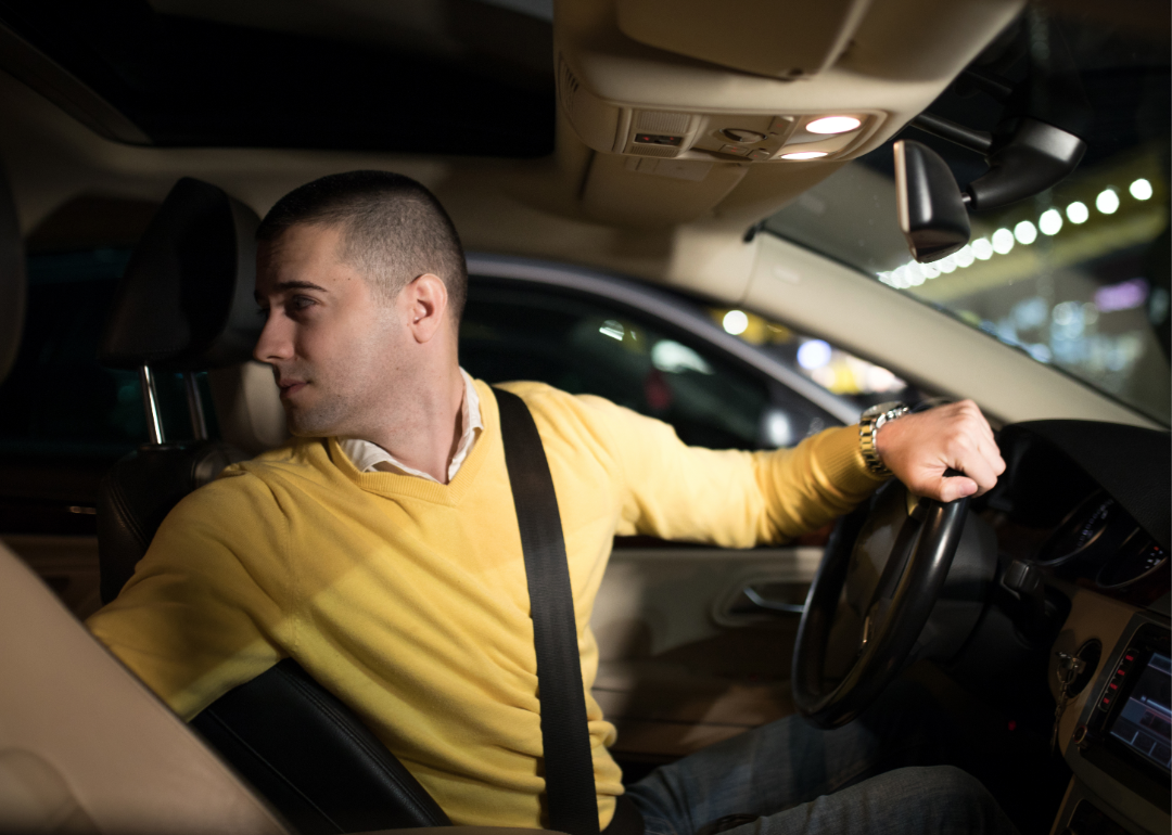 Man in a yellow sweater driving in reverse.