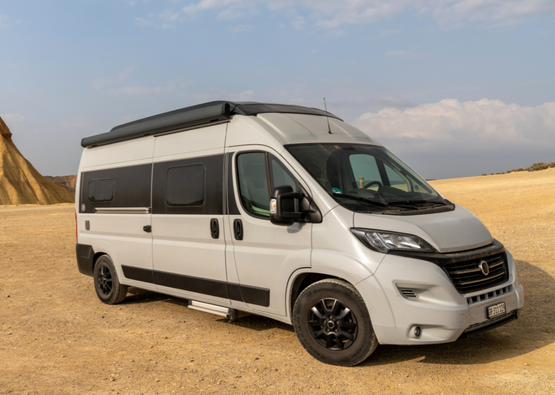 A gray van parked in a desert setting.