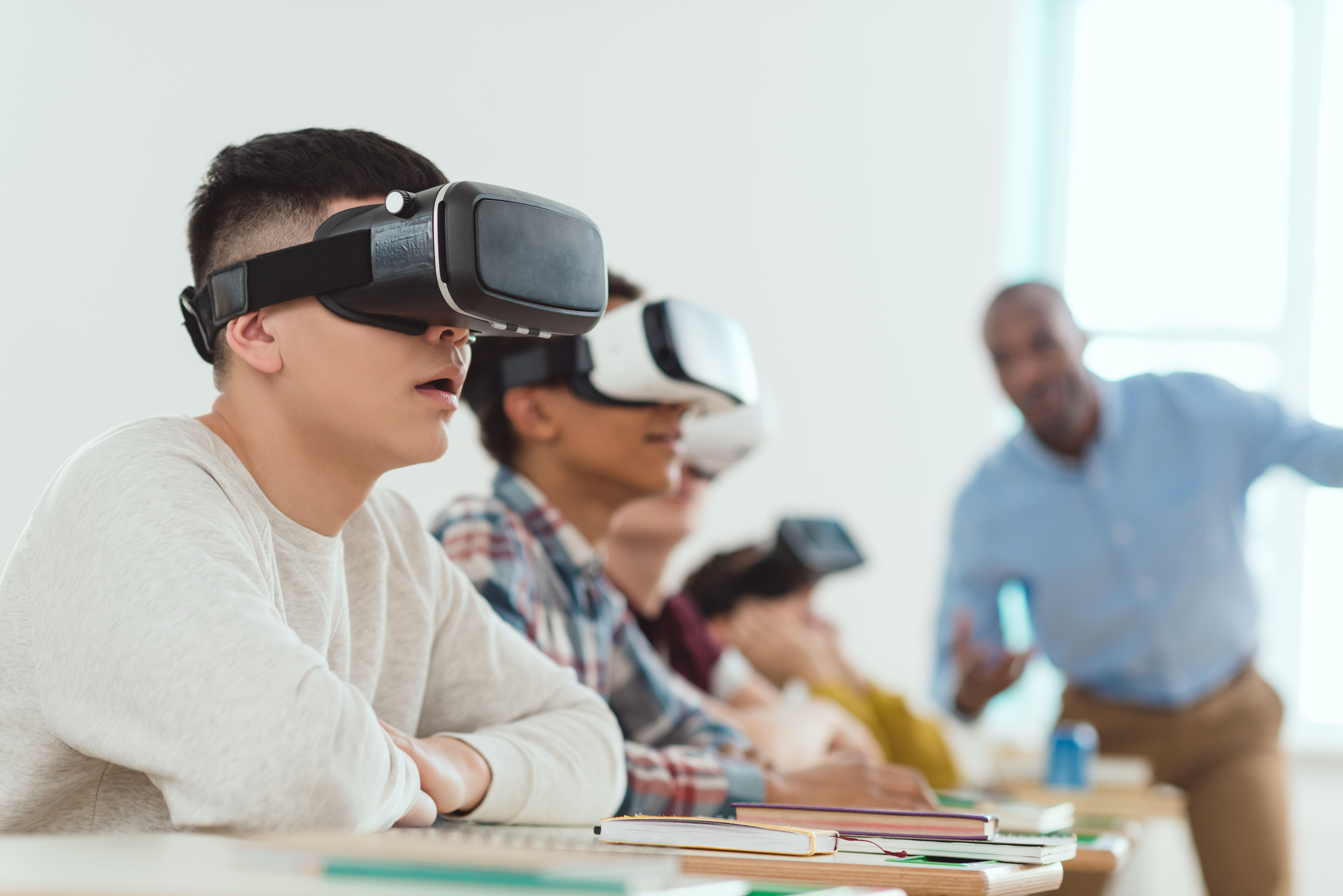 A teacher oversees students experiencing virtual reality.