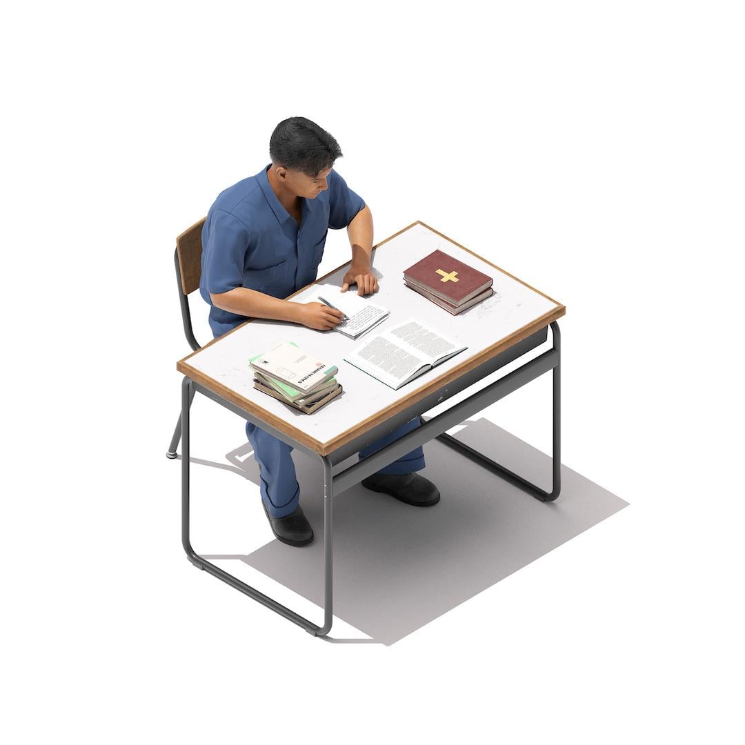 David DeLena, 45 A man sits at a desk looking at an open book, with another book closed nearby with a cross on its cover. He is writing on a pad of paper.