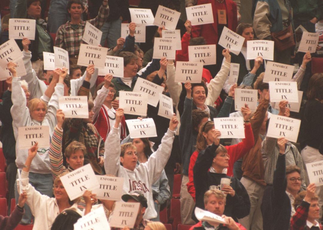 Protesters raising signs in support of Title IX