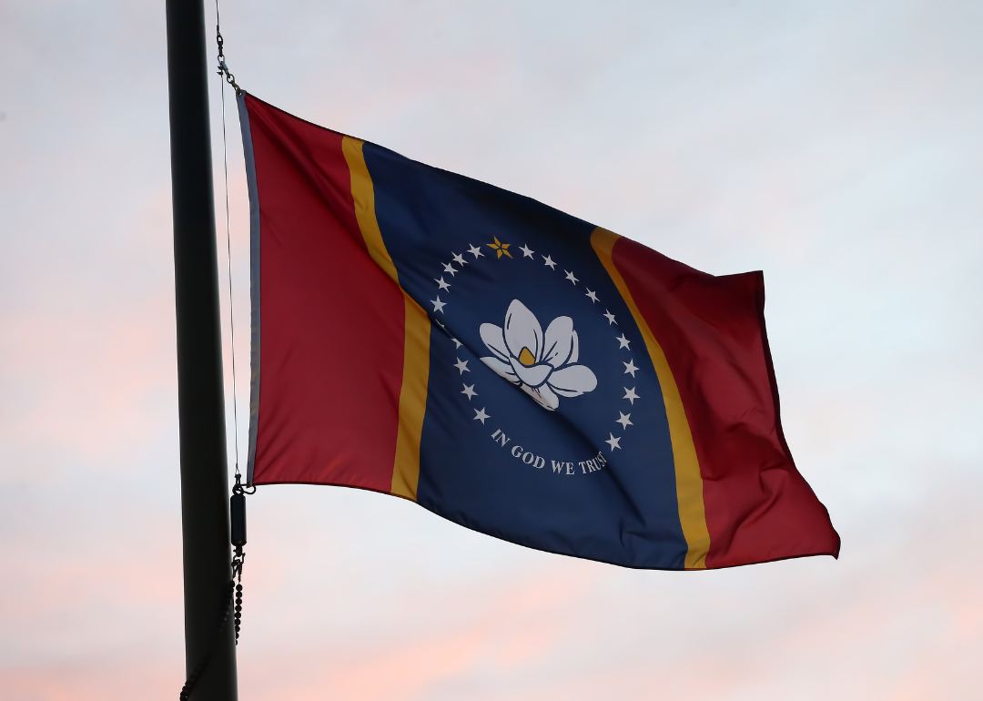 Mississippi state flag flies against a soft, pink and blue overcast sky.